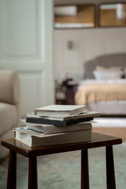 A close-up view of a living room corner featuring a hardwood floor with an ornate patterned area rug. On the floor, there is a yellow handheld vacuum cleaner connected to a black vacuum hose. Adjacent to the rug, a long black vacuum wand extends from the cleaner. In the background, a wooden sideboard with a black metal frame holds a white bust sculpture, a remote control, a stack of papers, and a chessboard. The room is well-lit, emphasizing the clean and polished surfaces of the wooden floor and the tidy appearance of the space, illustrating typical surface cleaning and maintenance with a focus on domestic cleaning at Islington Carpet Cleaning.